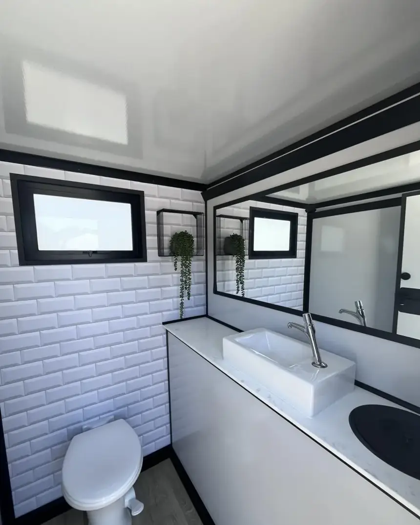 Restroom trailer interior with sink, mirror and window