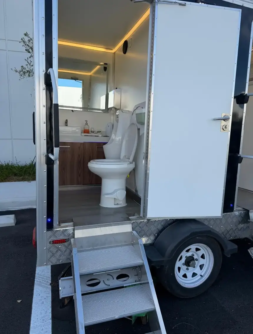 Open restroom trailer door showing lit interior