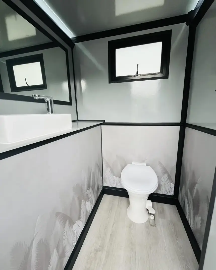 Restroom trailer stall with toilet and windows