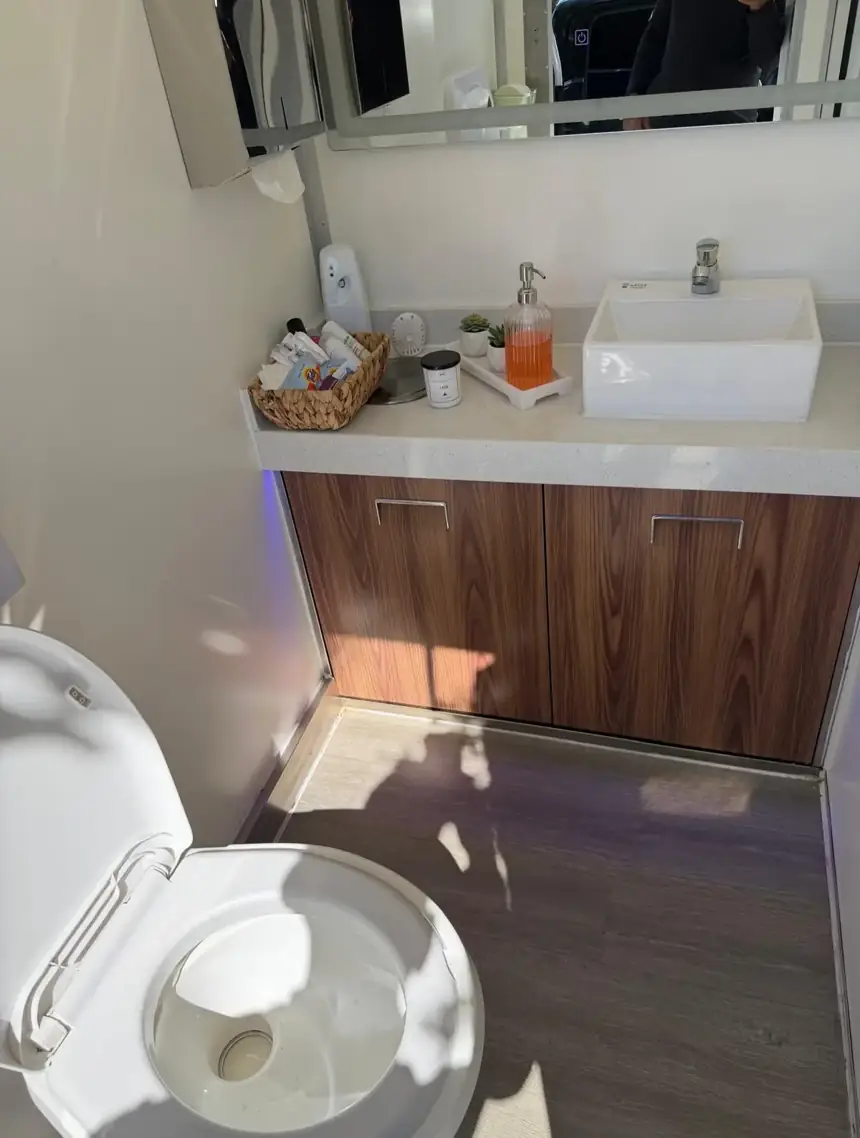 Restroom trailer stall with vanity sink and flush toilet